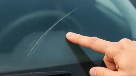 Rayure profonde sur une vitre de voiture avant réparation
