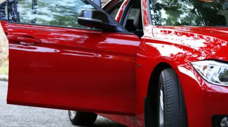 Voiture rouge prise de ce côté où on voit la portière d'une voiture ouverte avant une projection de peinture