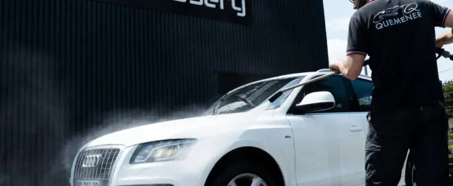 Homme entrain de laver un SUV Audi blanc en extérieur