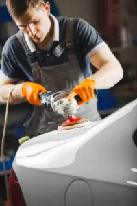 Artisan en carrosserie en train d'appliquer du polish pour rayure voiture sur portière