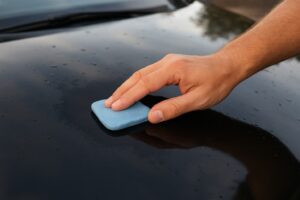 Application d'une clay bar pour décontaminer et enlever des tâches de peinture sur une carrosserie.
