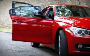 Voiture rouge prise de ce côté où on voit la portière d'une voiture ouverte avant une projection de peinture