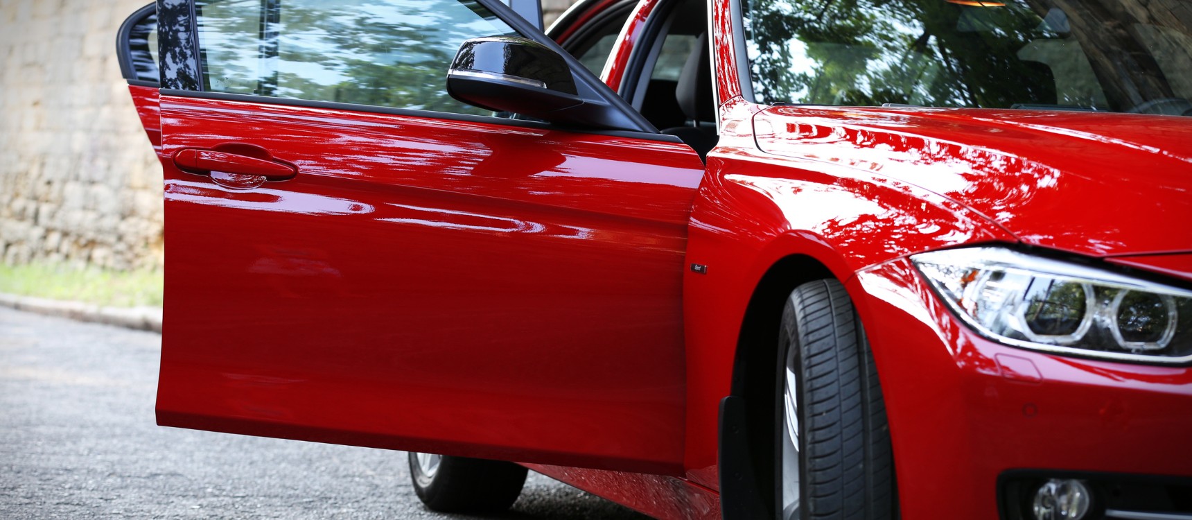 Voiture rouge prise de ce côté où on voit la portière d'une voiture ouverte avant une projection de peinture