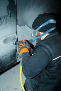 Photo d'un carrossier Zecarrossery en action de ponçage sur une rayure profonde