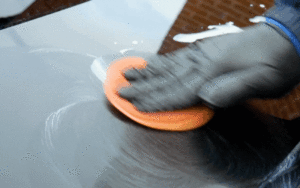 Application d'un polish avec un chiffon microfibre pour enlever une trace de frottement sur une carrosserie.