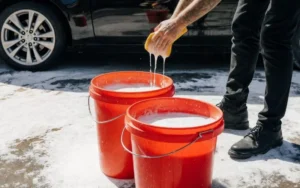 lavage à la main d'une voiture avec la technique des deux seaux.