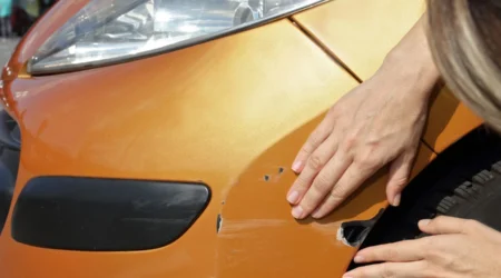 Rayure profonde sur la carrosserie d'une voiture dans un parking.