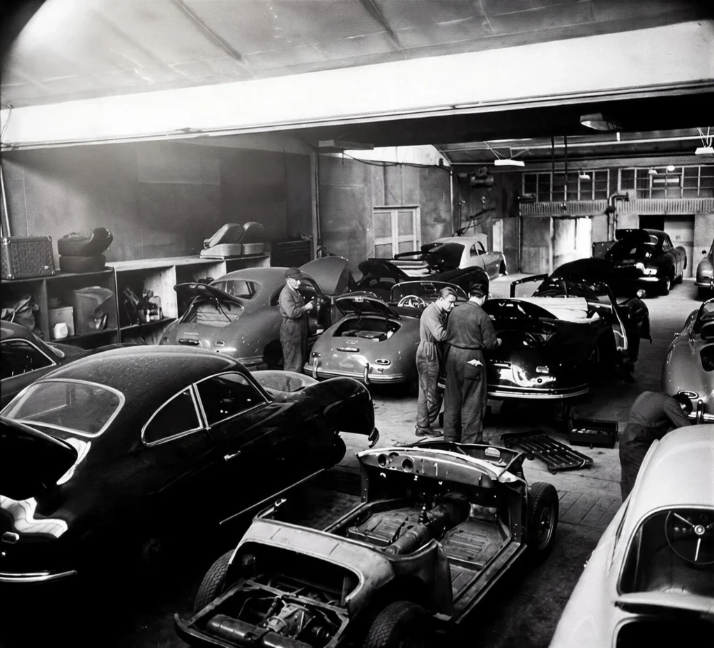PHoto old school d'artisans dans une carrosserie qui réparent des voitures